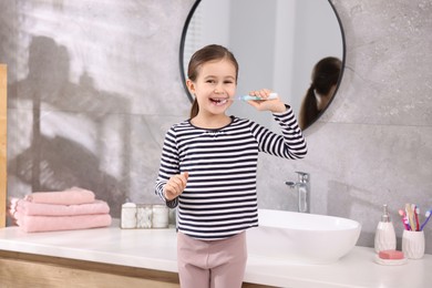 Photo of Cute girl brushing her teeth in bathroom