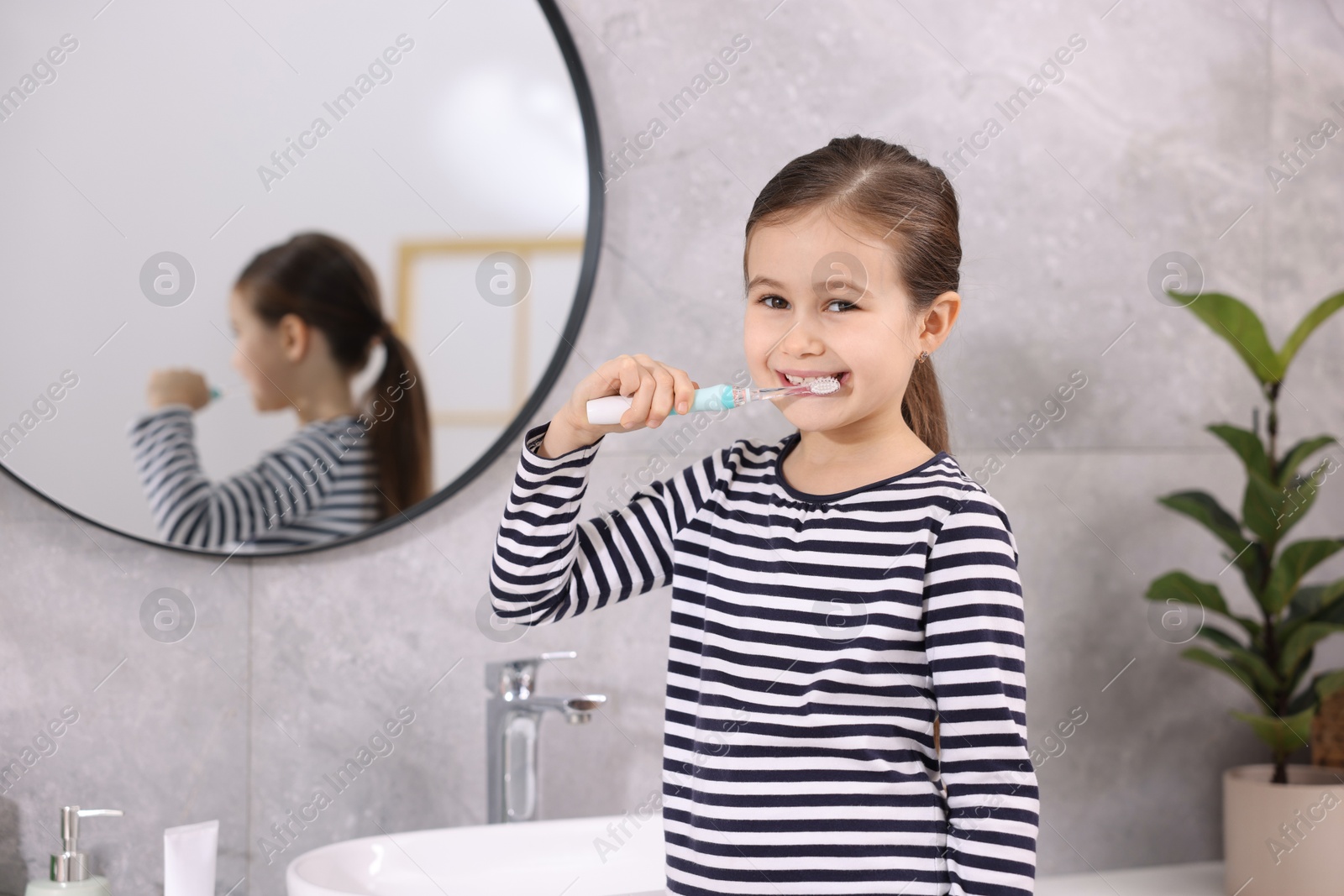 Photo of Cute girl brushing her teeth in bathroom