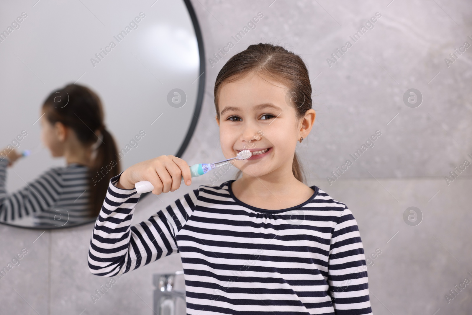 Photo of Cute girl brushing her teeth in bathroom