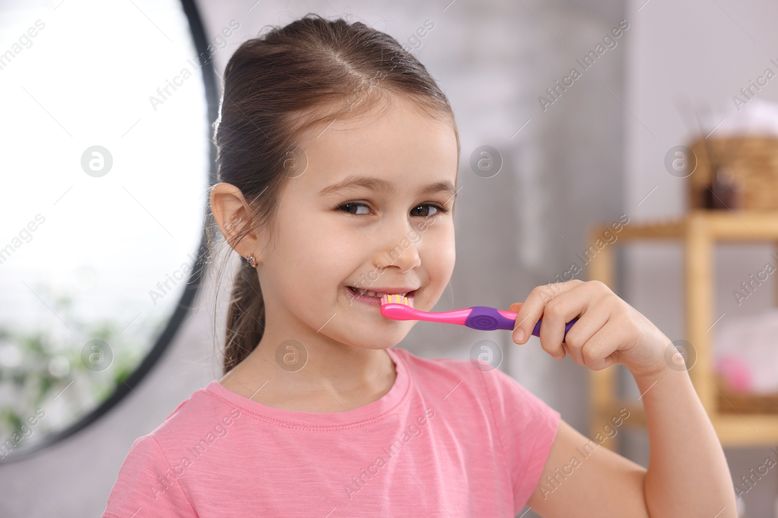 Photo of Cute girl brushing her teeth in bathroom