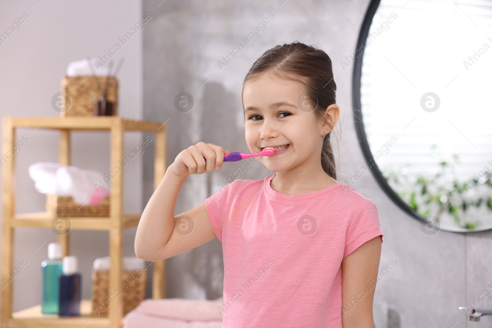 Photo of Cute girl brushing her teeth in bathroom