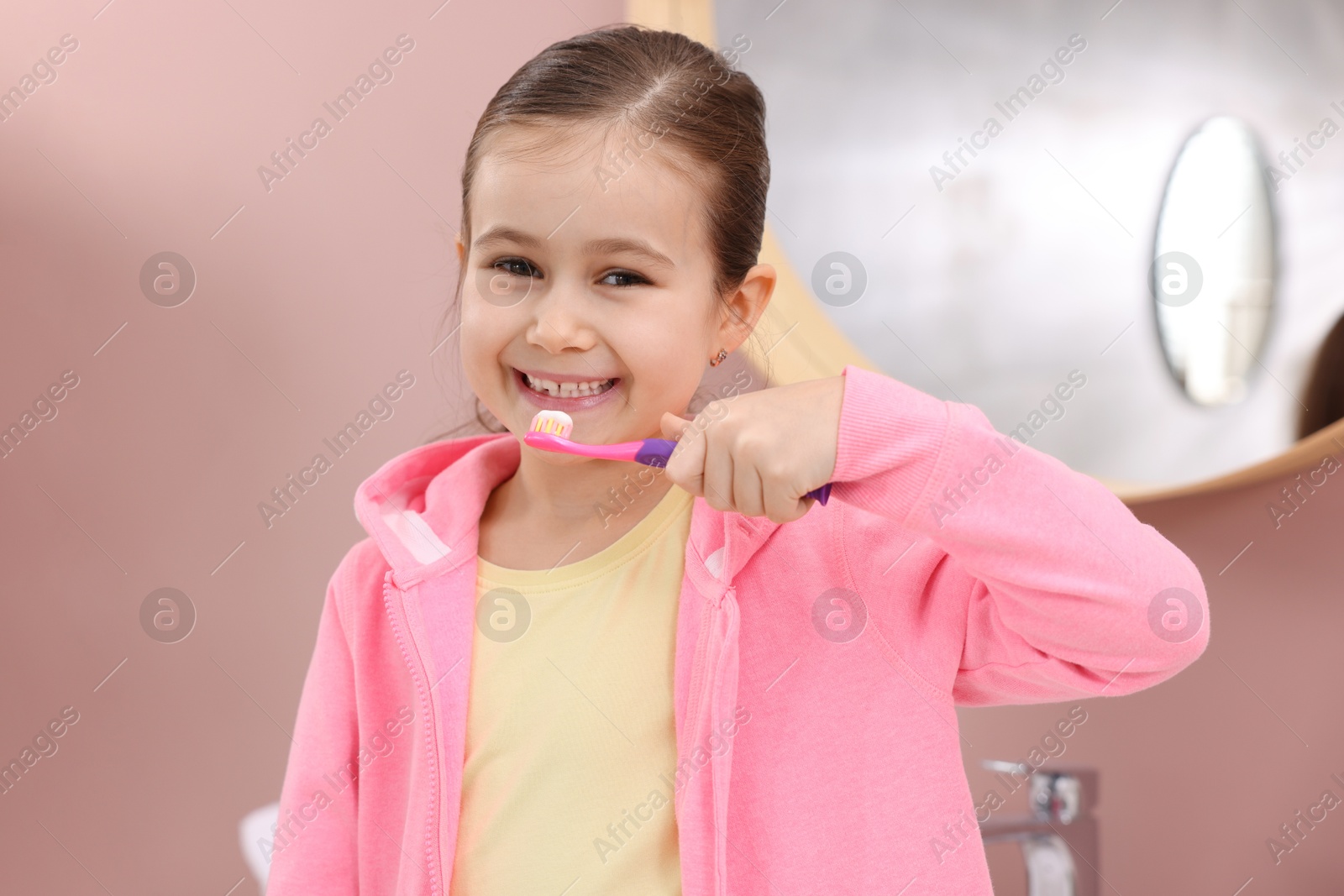 Photo of Cute girl brushing her teeth in bathroom