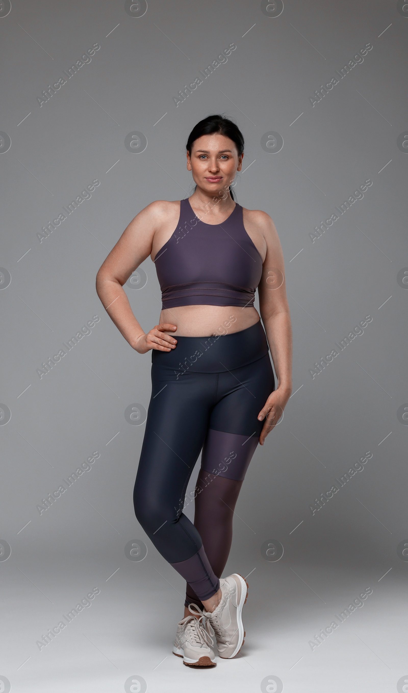 Photo of Plus size woman in gym clothes on grey background