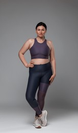 Photo of Plus size woman in gym clothes on grey background