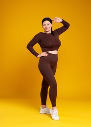 Photo of Plus size woman in gym clothes on orange background