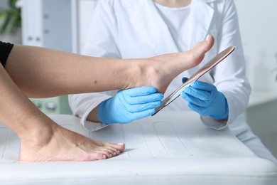 Photo of Doctor fitting insole to patient's foot in hospital, closeup