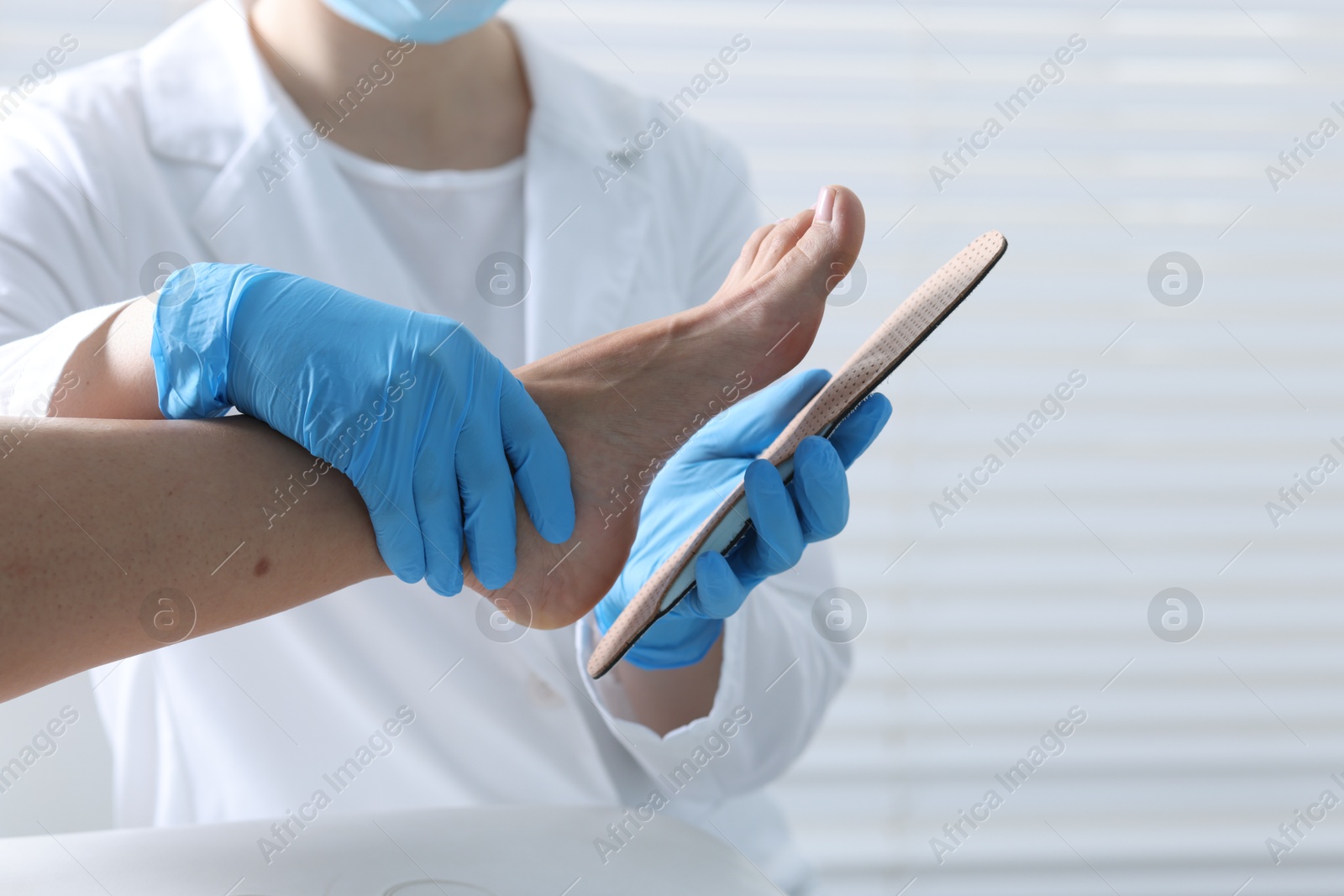 Photo of Doctor fitting insole to patient's foot in hospital, closeup