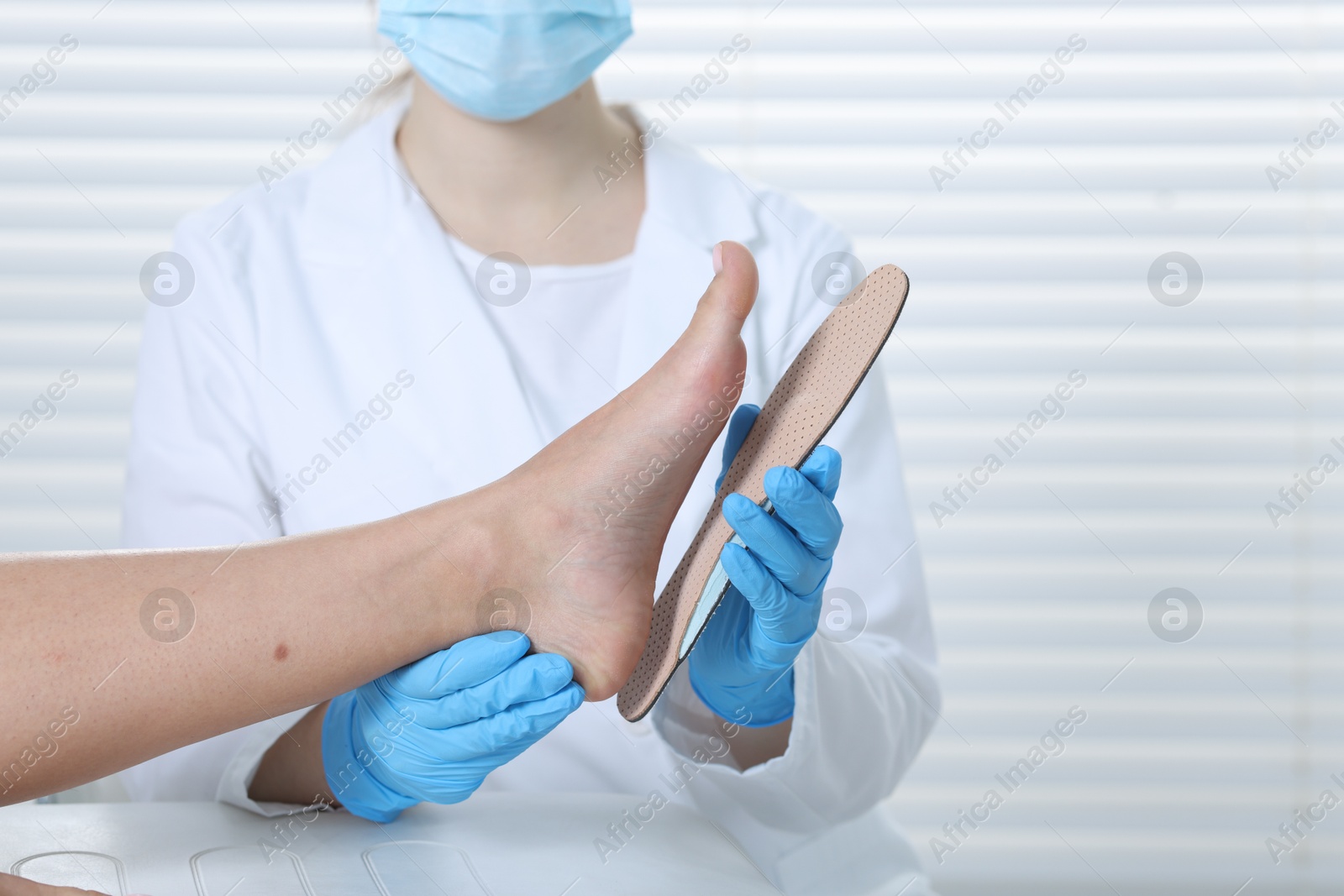 Photo of Doctor fitting insole to patient's foot in hospital, closeup