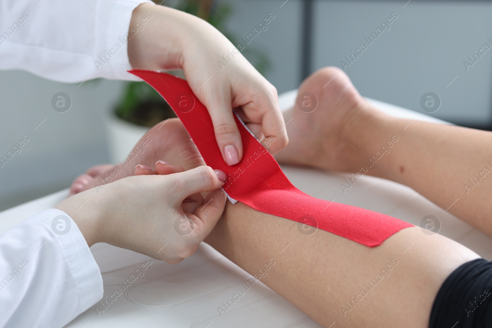 Photo of Doctor applying kinesio tapes to patient's foot in hospital, closeup