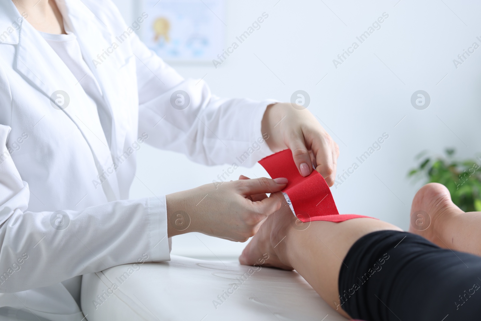 Photo of Doctor applying kinesio tapes to patient's foot in hospital, closeup