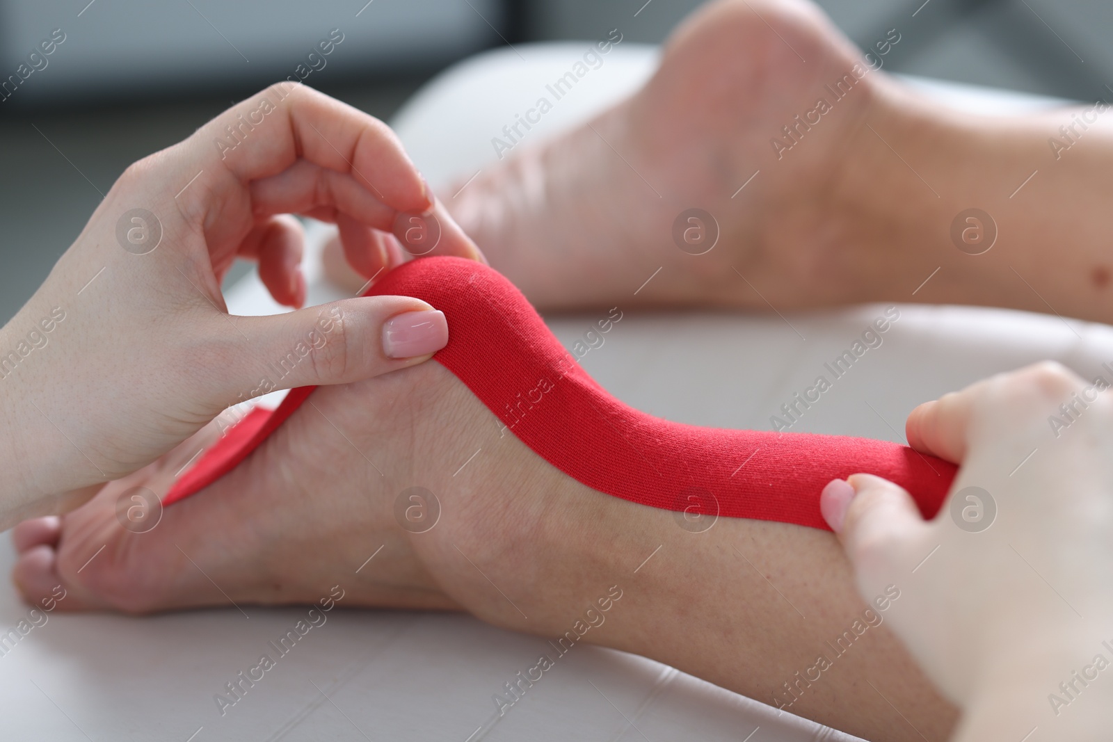 Photo of Doctor applying kinesio tapes to patient's foot in hospital, closeup