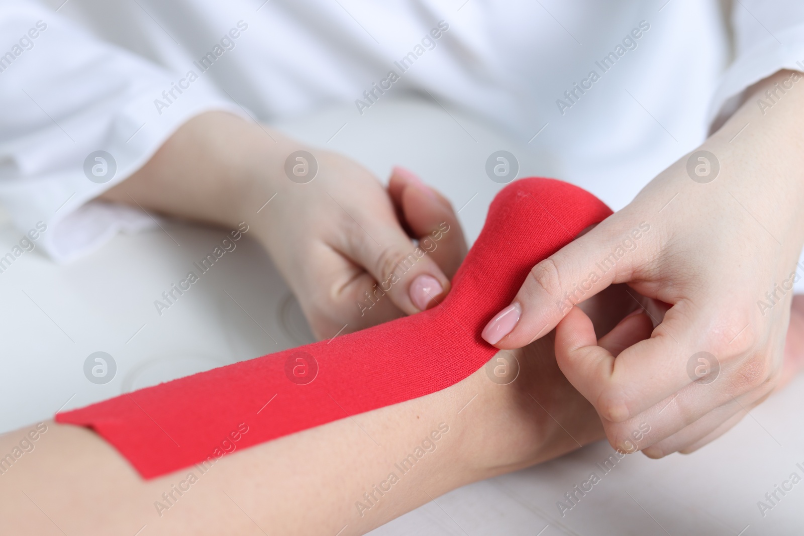 Photo of Doctor applying kinesio tapes to patient's foot in hospital, closeup