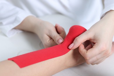 Photo of Doctor applying kinesio tapes to patient's foot in hospital, closeup