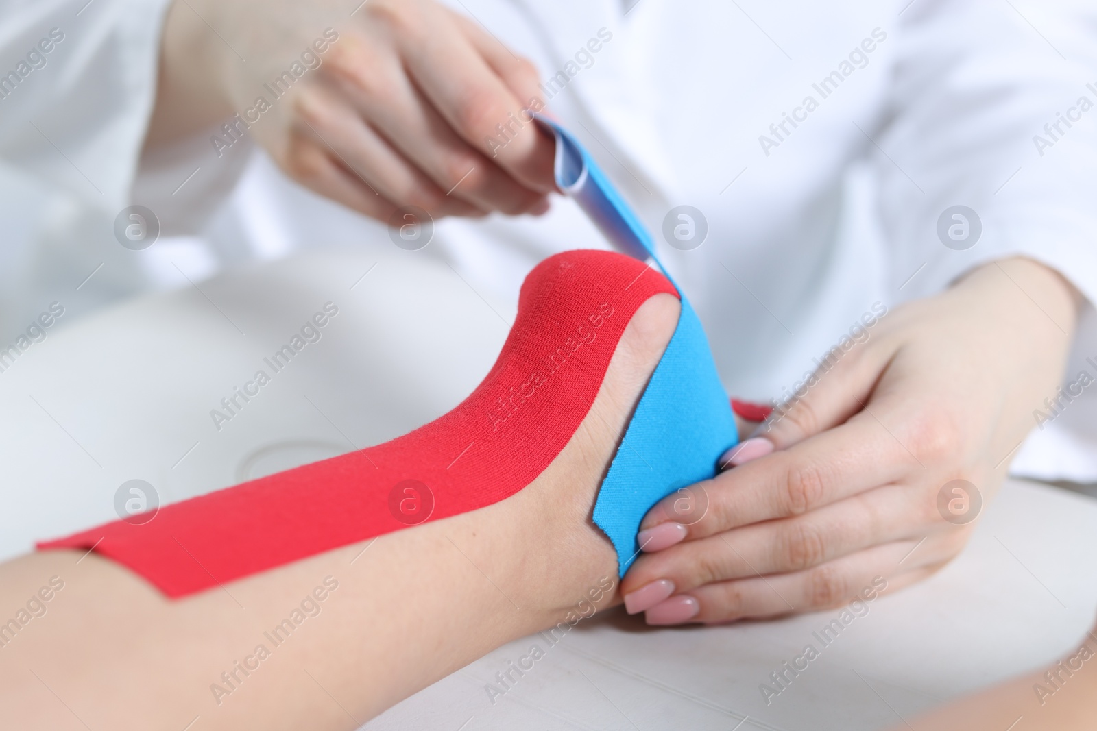 Photo of Doctor applying kinesio tapes to patient's foot in hospital, closeup