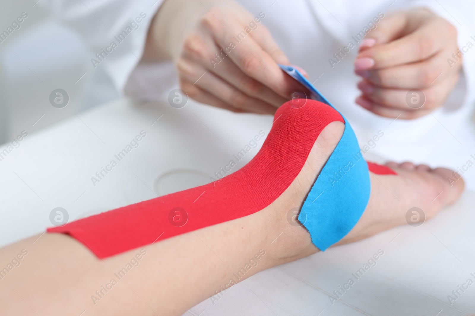 Photo of Doctor applying kinesio tapes to patient's foot in hospital, closeup