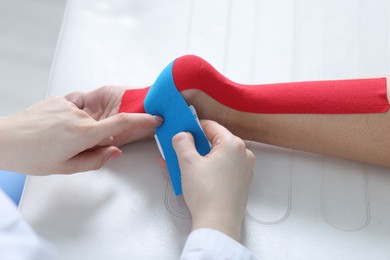 Photo of Doctor applying kinesio tapes to patient's foot in hospital, closeup