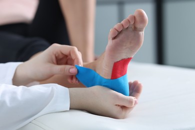 Photo of Doctor applying kinesio tapes to patient's foot in hospital, closeup