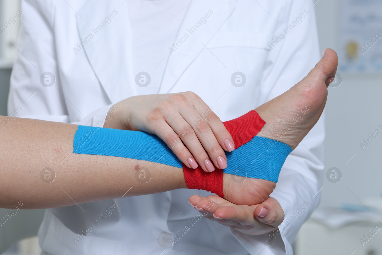 Photo of Doctor applying kinesio tapes to patient's foot in hospital, closeup