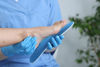 Photo of Doctor fitting insole to patient's foot in hospital, closeup