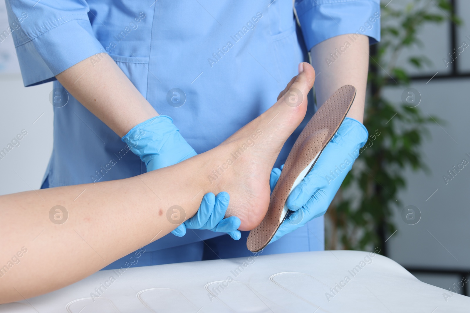 Photo of Doctor fitting insole to patient's foot in hospital, closeup