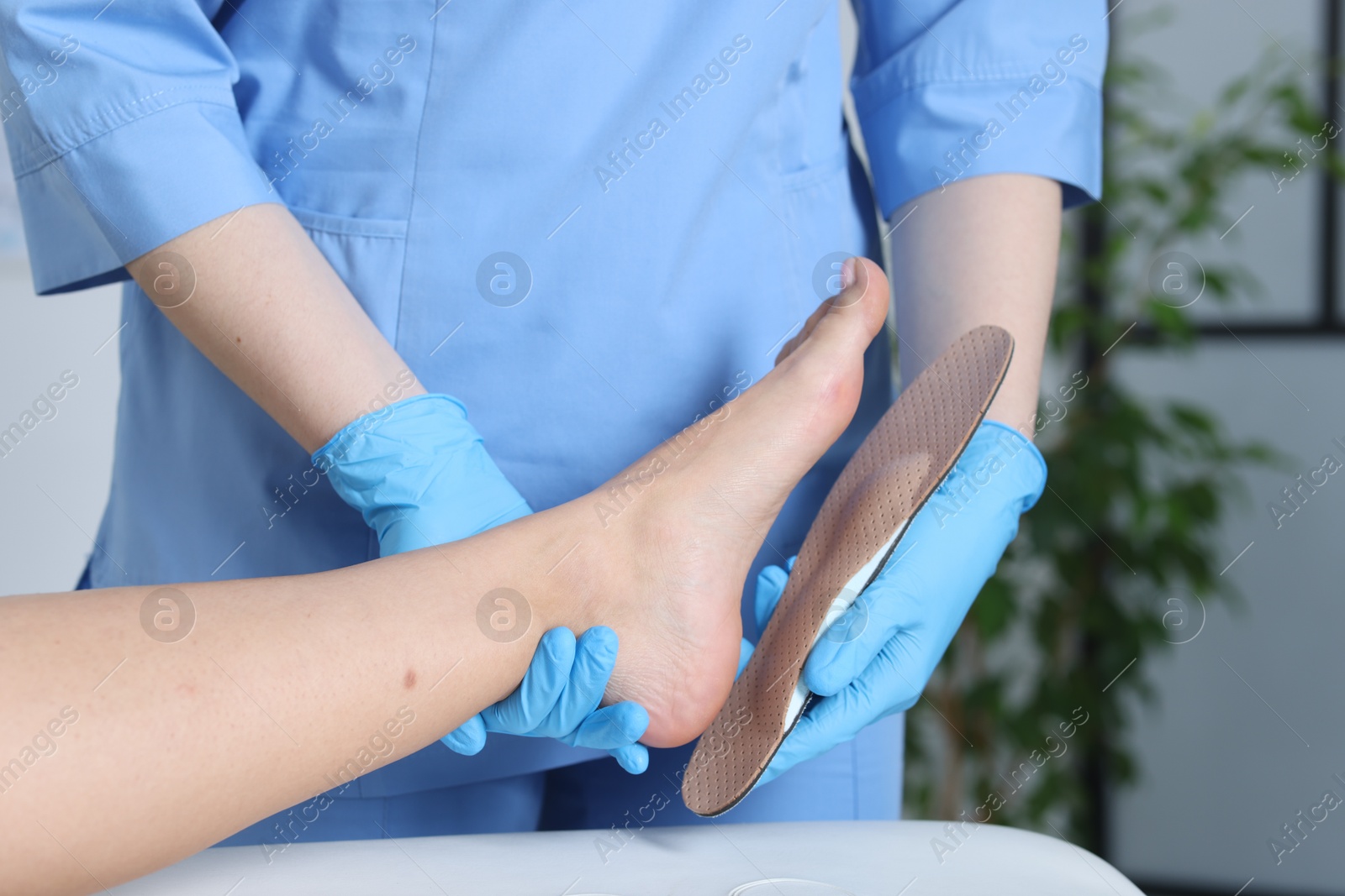 Photo of Doctor fitting insole to patient's foot in hospital, closeup