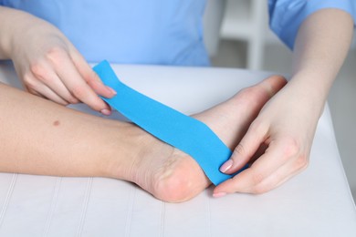 Photo of Doctor applying kinesio tapes to patient's foot in hospital, closeup