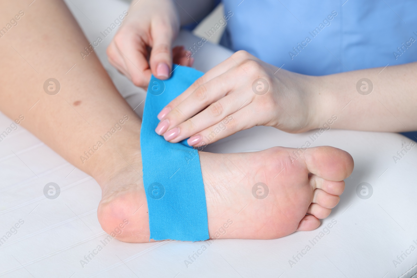 Photo of Doctor applying kinesio tapes to patient's foot in hospital, closeup