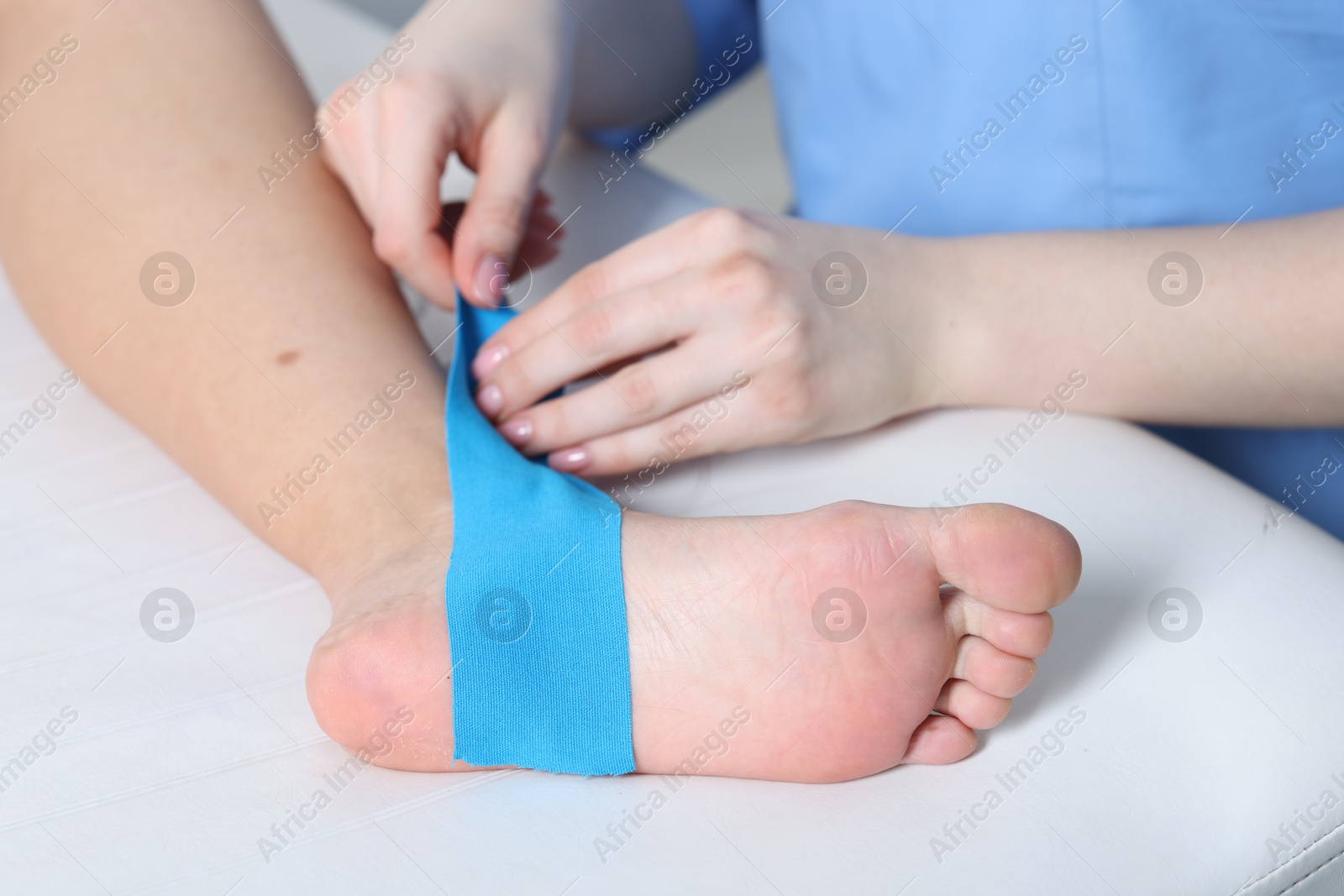 Photo of Doctor applying kinesio tapes to patient's foot in hospital, closeup