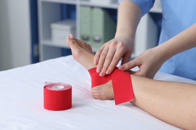 Photo of Doctor applying kinesio tapes to patient's foot in hospital, closeup