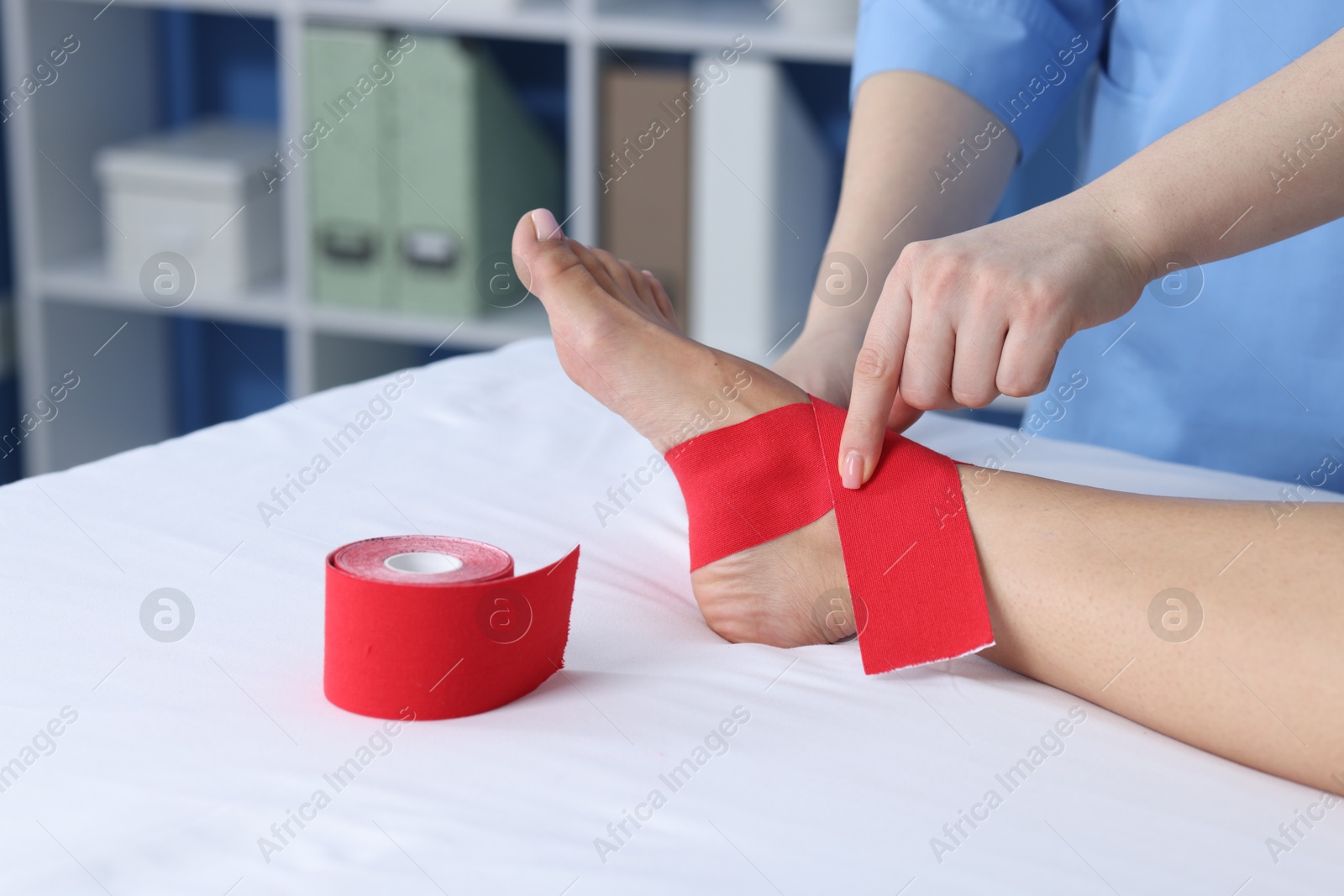 Photo of Doctor applying kinesio tapes to patient's foot in hospital, closeup