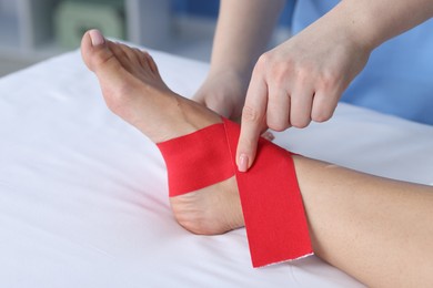 Photo of Doctor applying kinesio tapes to patient's foot in hospital, closeup