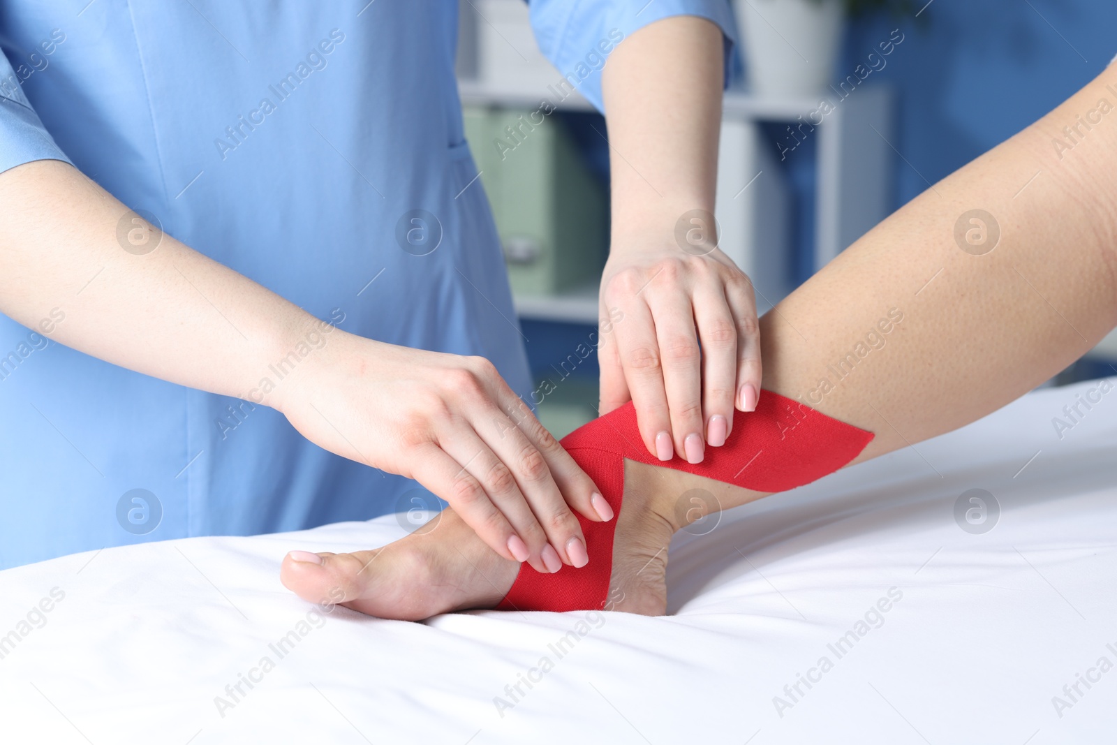 Photo of Doctor applying kinesio tapes to patient's foot in hospital, closeup