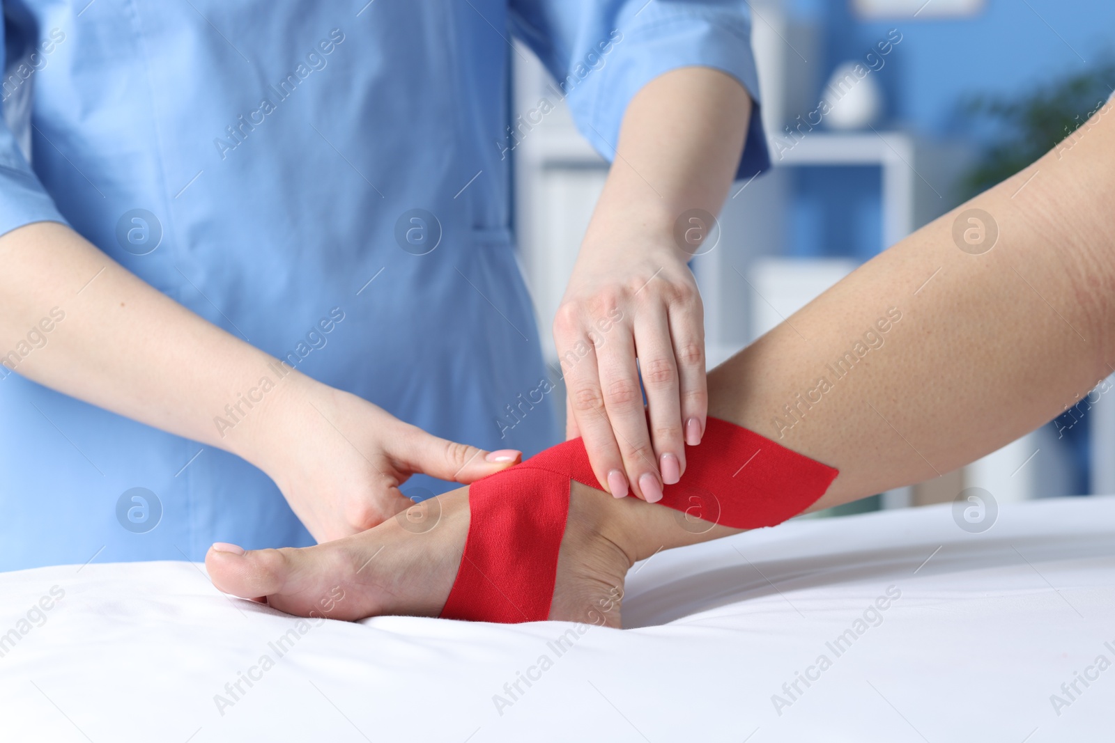 Photo of Doctor applying kinesio tapes to patient's foot in hospital, closeup