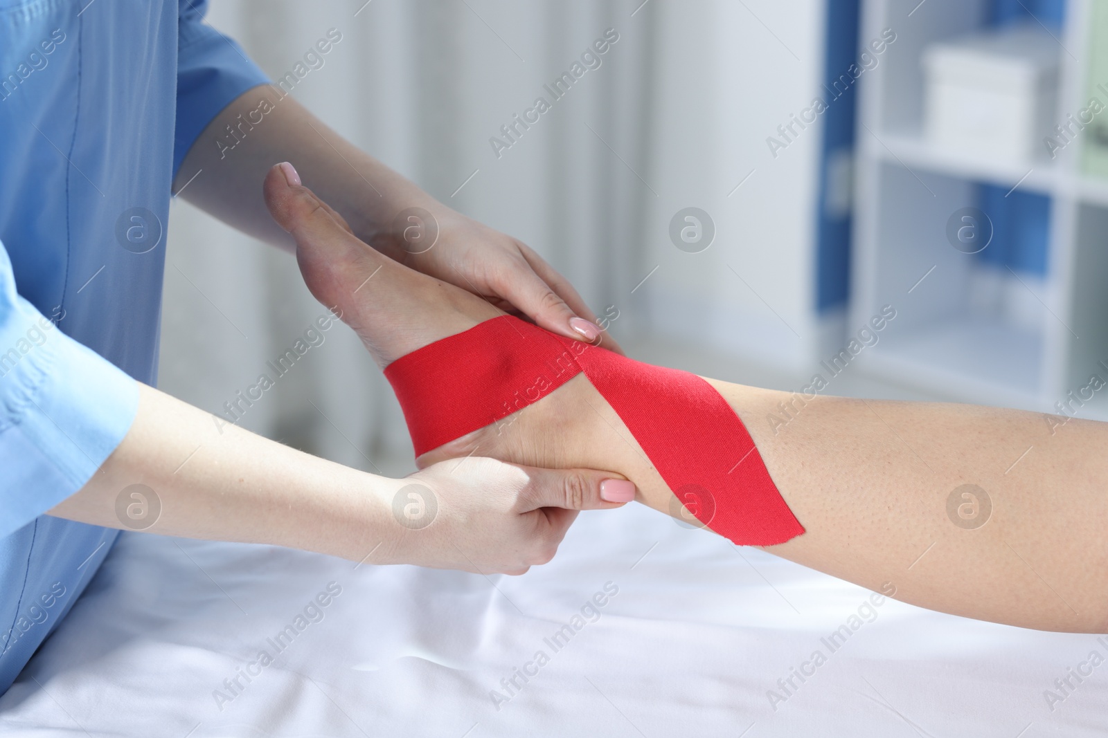 Photo of Doctor applying kinesio tapes to patient's foot in hospital, closeup