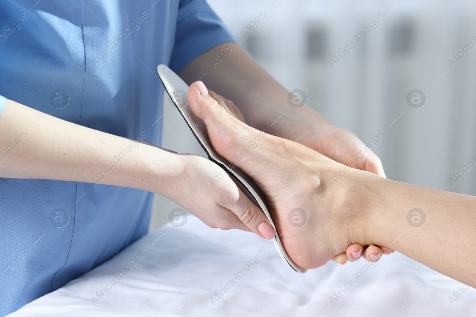 Photo of Doctor fitting insole to patient's foot in hospital, closeup