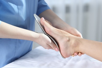 Photo of Doctor fitting insole to patient's foot in hospital, closeup