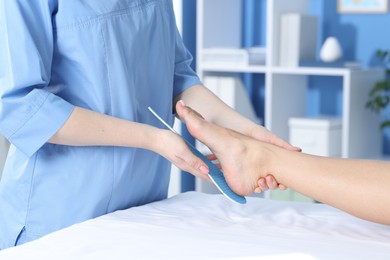 Photo of Doctor fitting insole to patient's foot in hospital, closeup