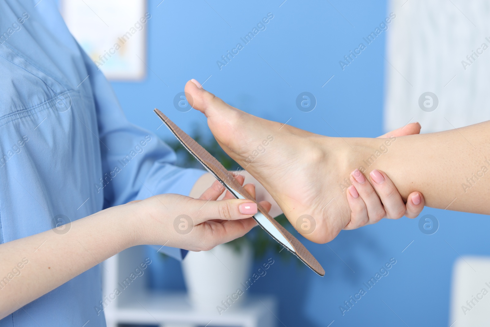 Photo of Doctor fitting insole to patient's foot in hospital, closeup