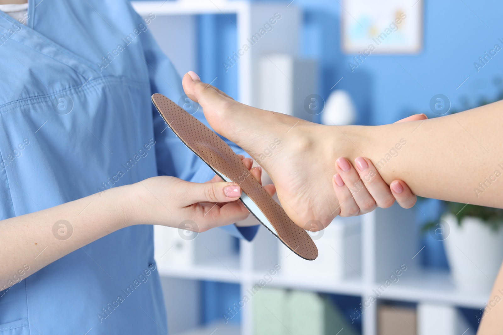 Photo of Doctor fitting insole to patient's foot in hospital, closeup