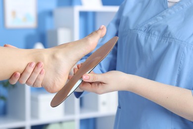 Photo of Doctor fitting insole to patient's foot in hospital, closeup