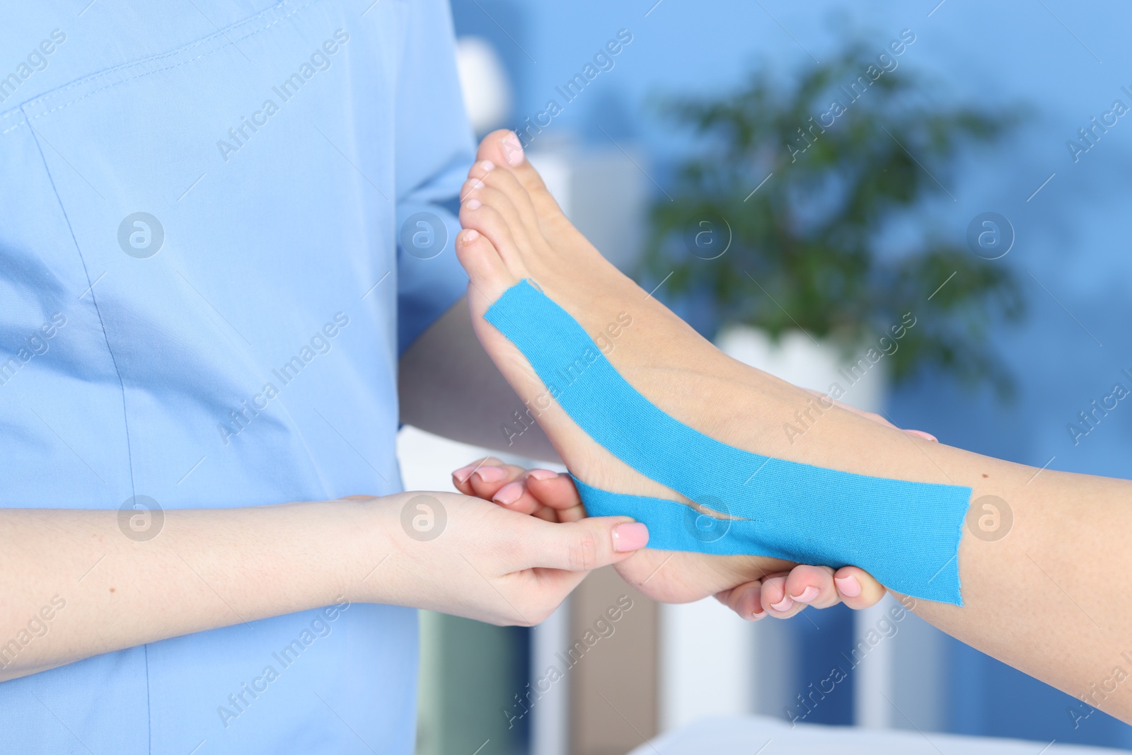 Photo of Doctor applying kinesio tapes to patient's foot in hospital, closeup