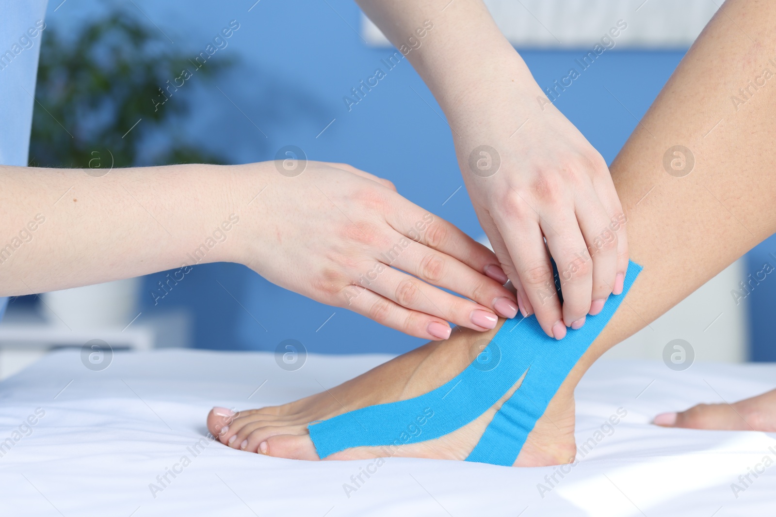 Photo of Doctor applying kinesio tapes to patient's foot in hospital, closeup