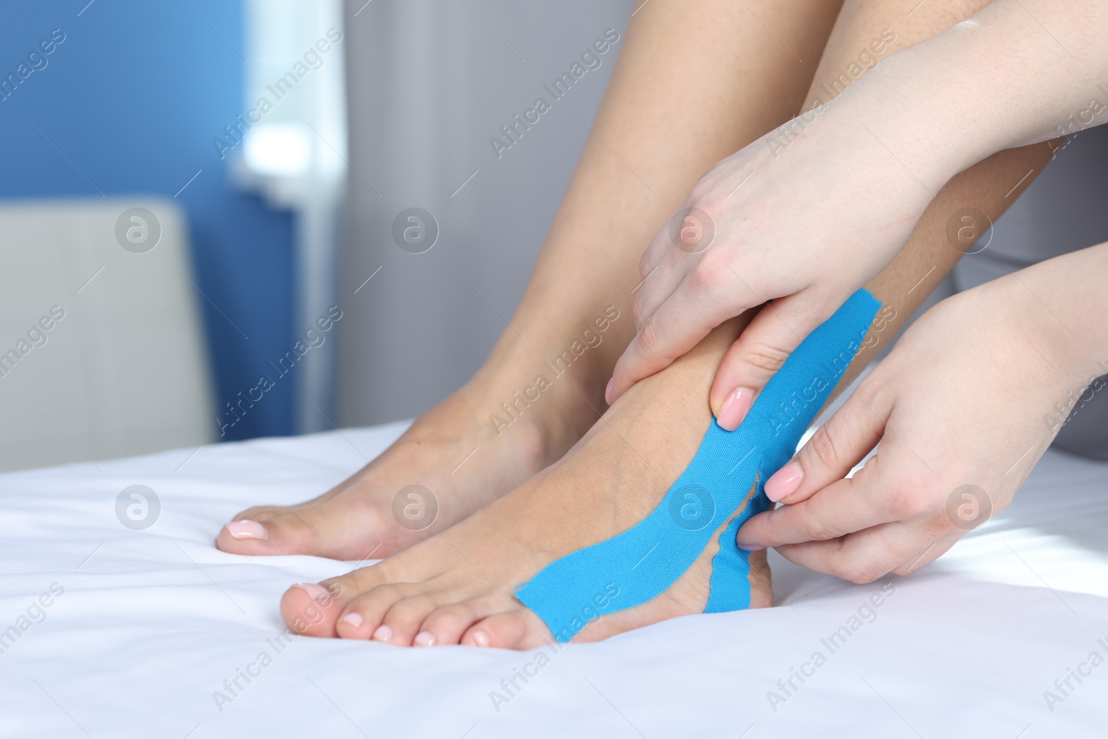 Photo of Doctor applying kinesio tapes to patient's foot in hospital, closeup