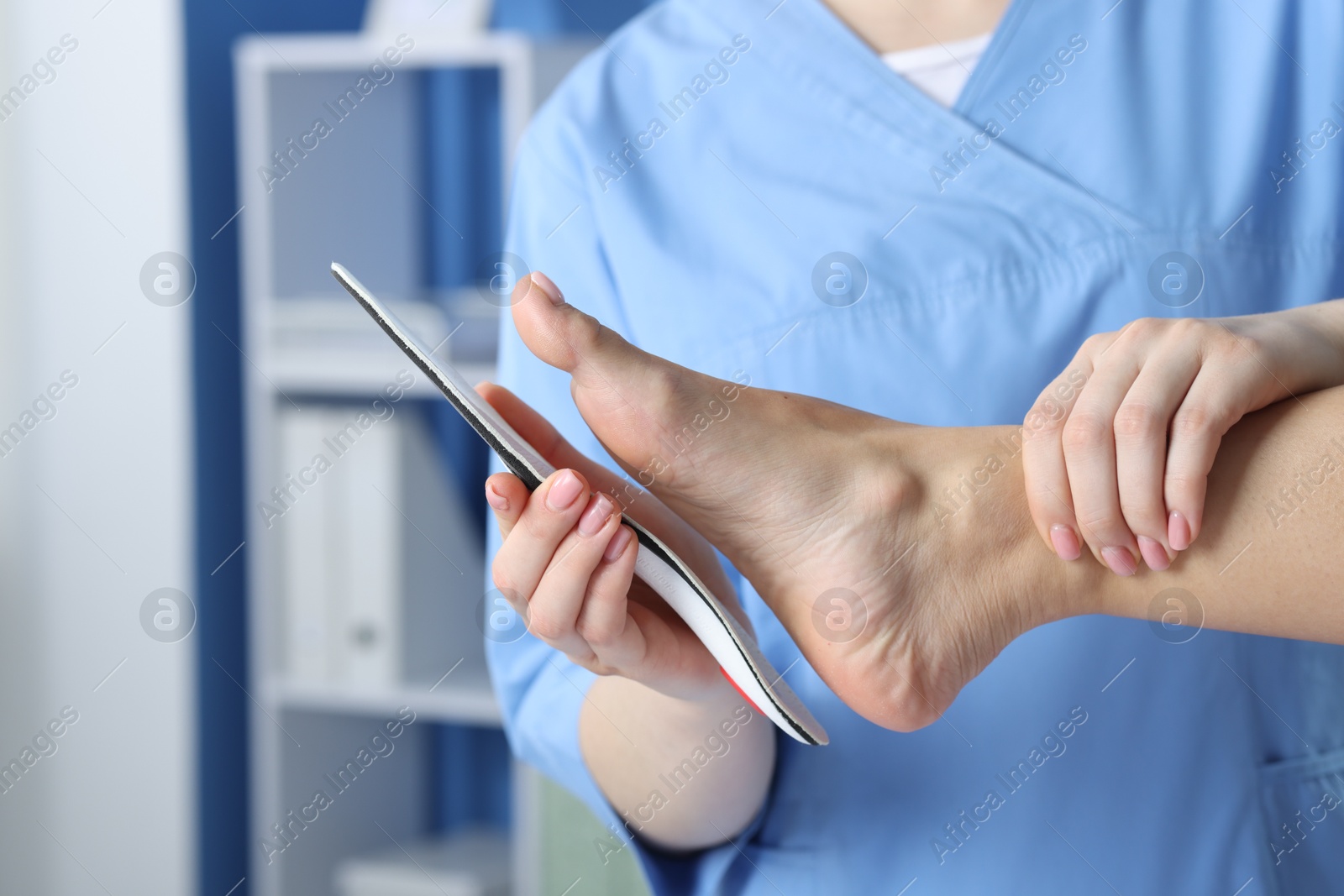 Photo of Doctor fitting insole to patient's foot in hospital, closeup