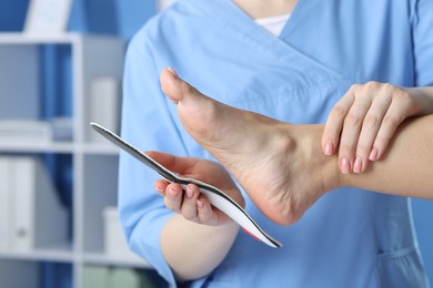 Photo of Doctor fitting insole to patient's foot in hospital, closeup