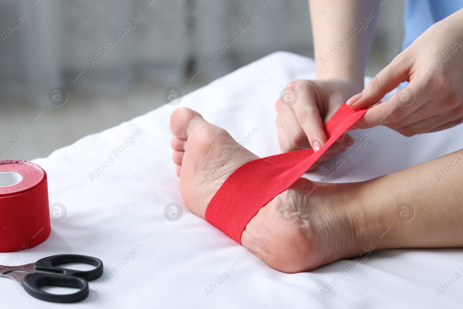 Photo of Doctor applying kinesio tapes to patient's foot in hospital, closeup