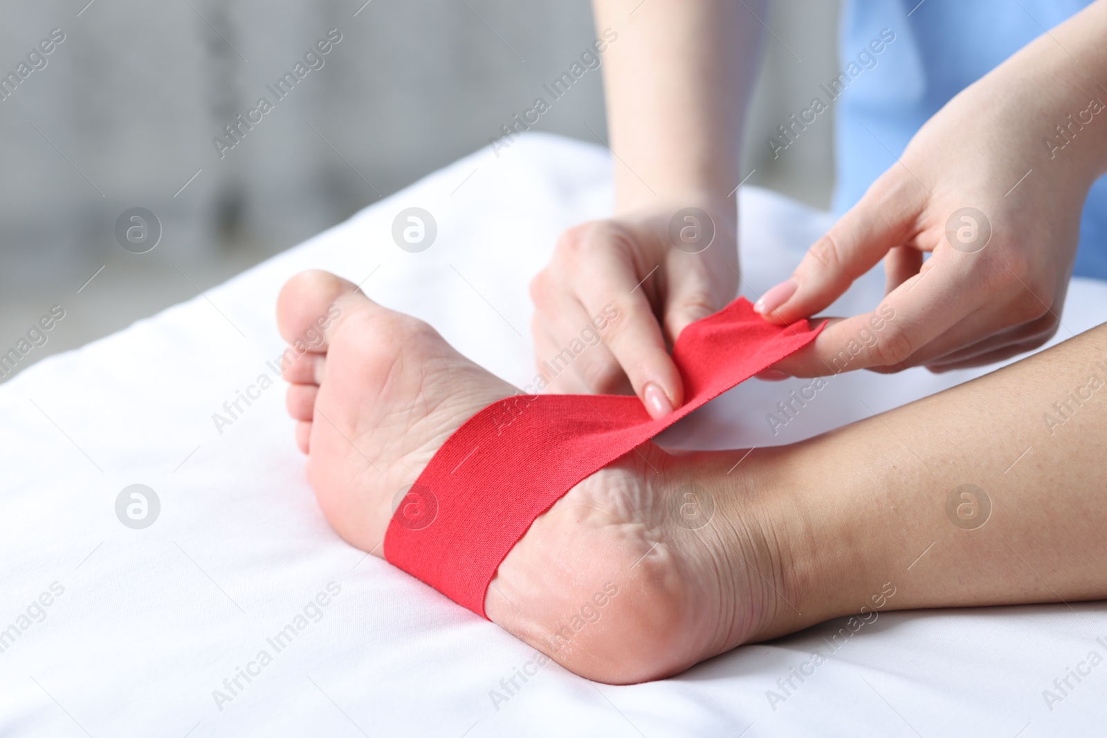 Photo of Doctor applying kinesio tapes to patient's foot in hospital, closeup