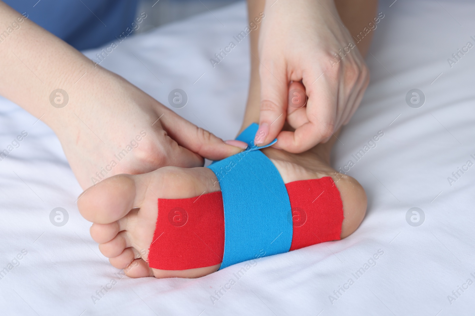 Photo of Doctor applying kinesio tapes to patient's foot in hospital, closeup