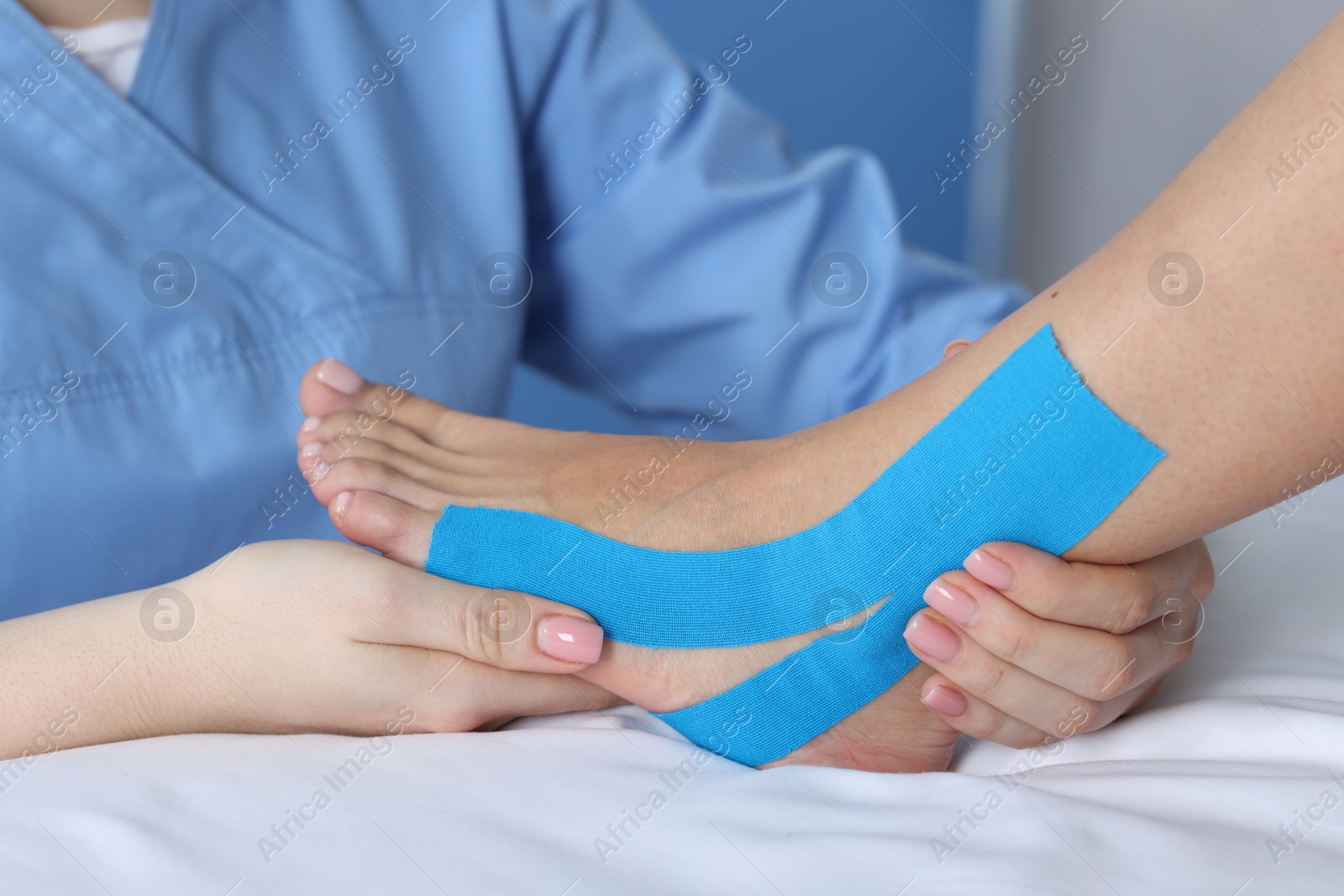 Photo of Doctor applying kinesio tapes to patient's foot in hospital, closeup