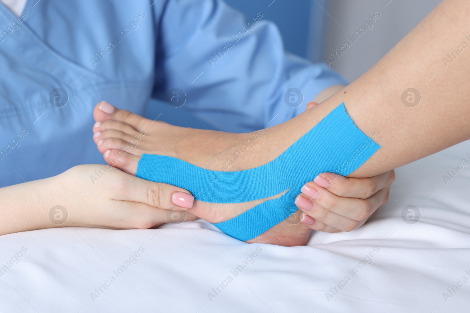 Photo of Doctor applying kinesio tapes to patient's foot in hospital, closeup